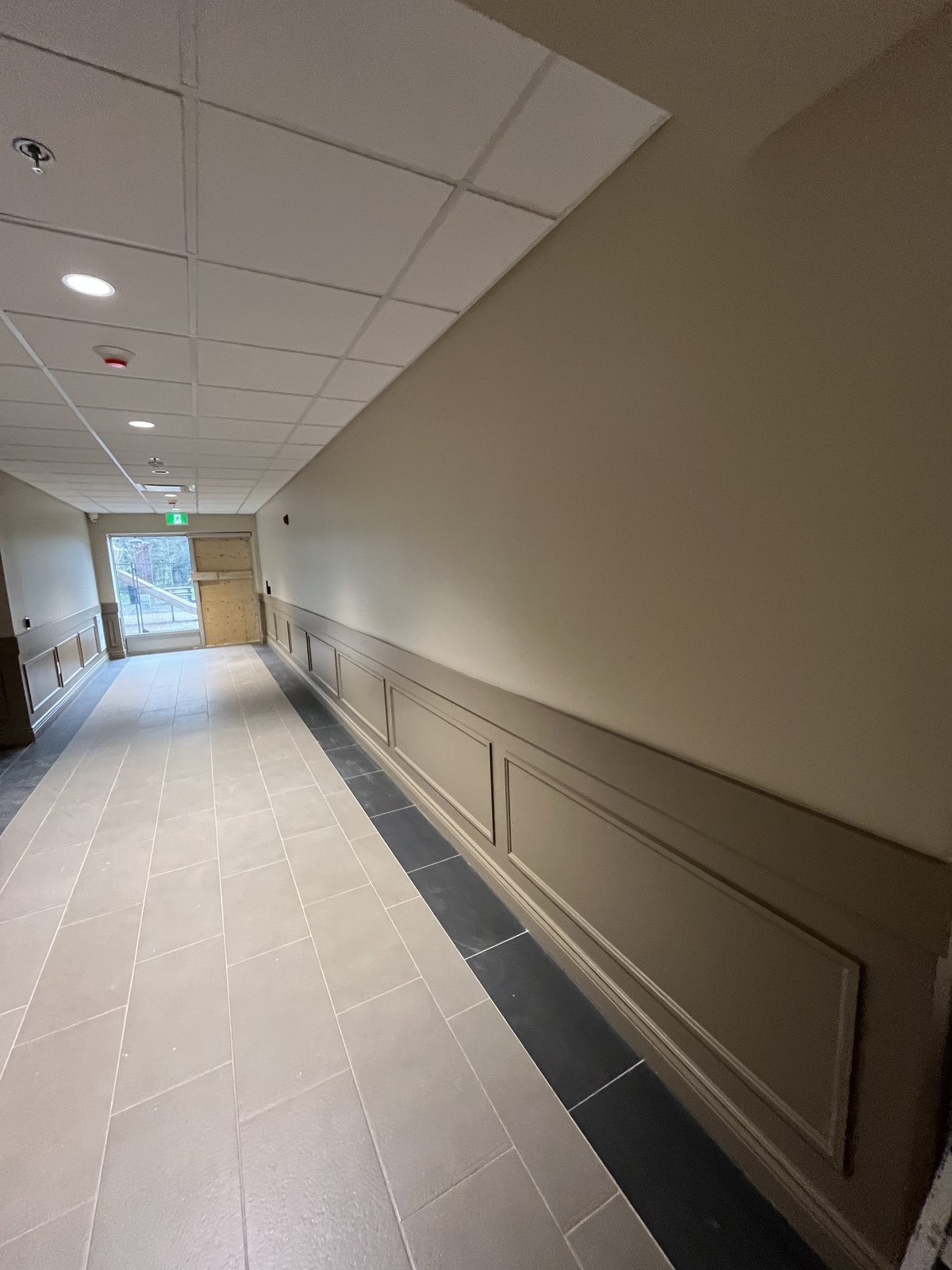 Painted panel wainscoting and beige walls along a tiled corridor at 40 Polonia in Brampton