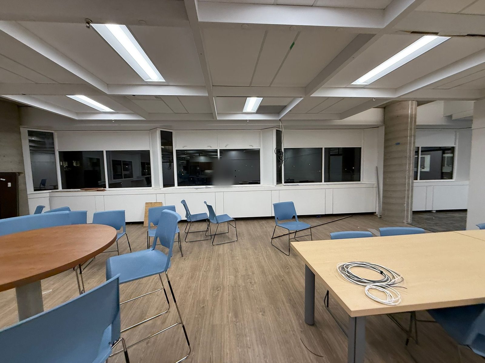Café seating area with blue chairs below white painted interior window walls and ceiling beams on the 6th floor at 4900 Yonge Street, Toronto
