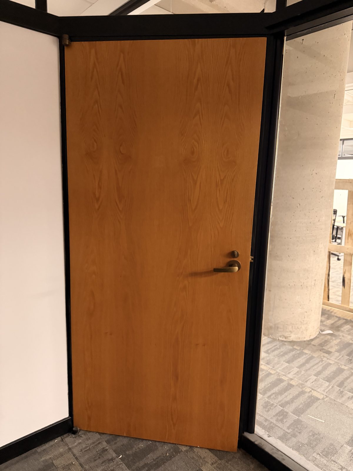 Wood-veneer door beside a glass partition and concrete column on the 6th floor at 4900 Yonge Street, Toronto
