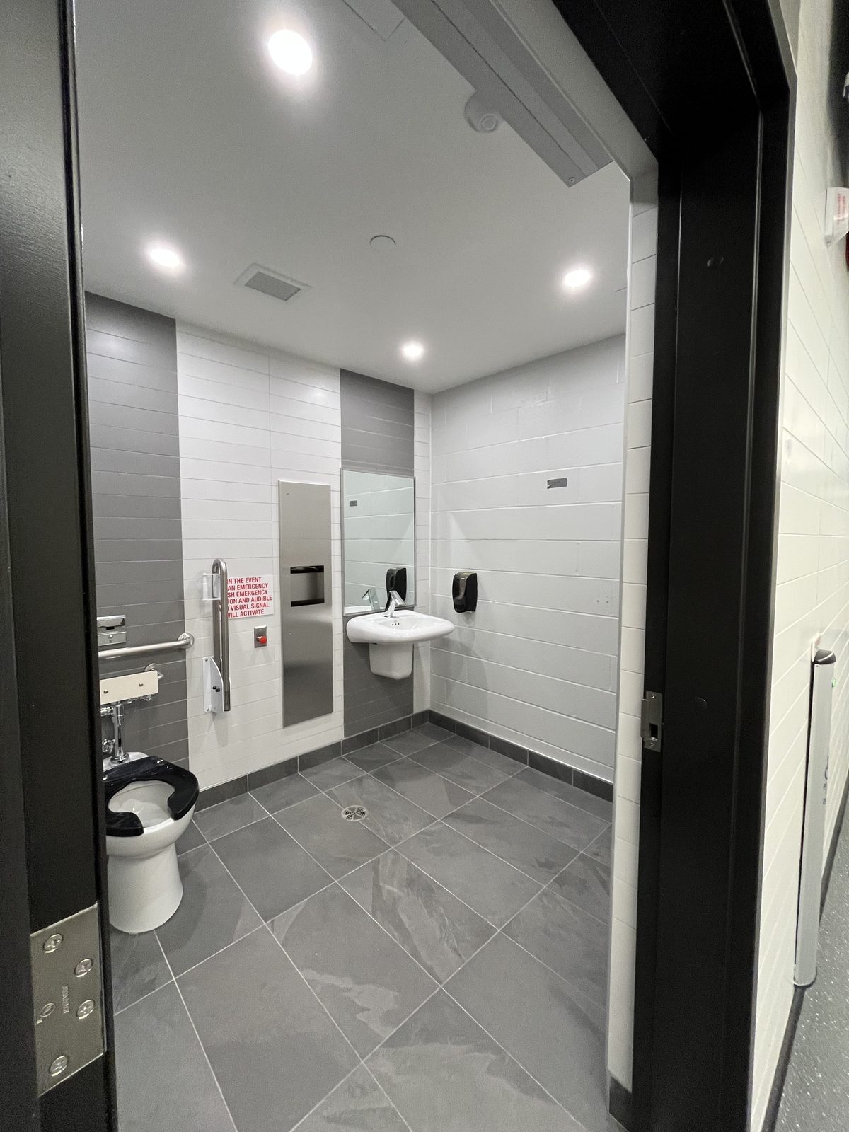 Barrier-free washroom with white and grey tile walls, grab bars and grey floor tile at the Albert McCormick Community Centre in Waterloo