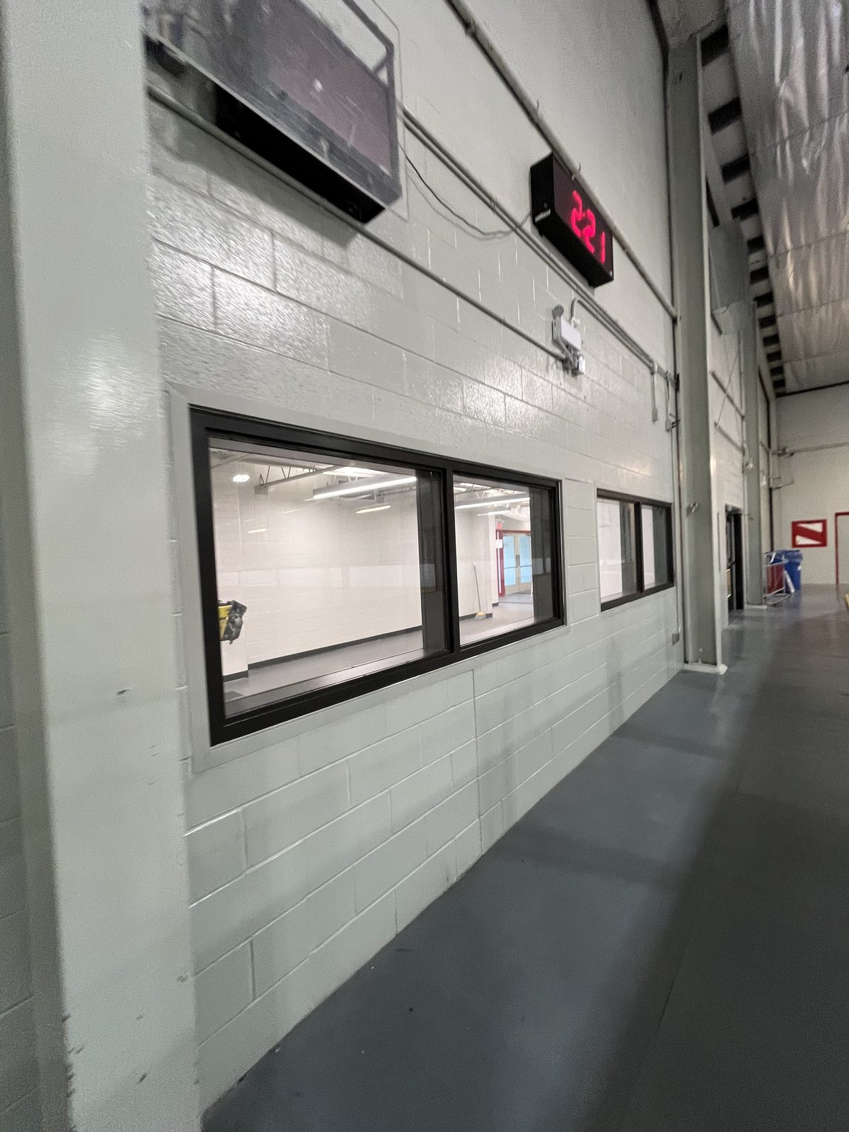 Corridor with light painted concrete block walls and black-framed interior windows at the Albert McCormick Community Centre in Waterloo