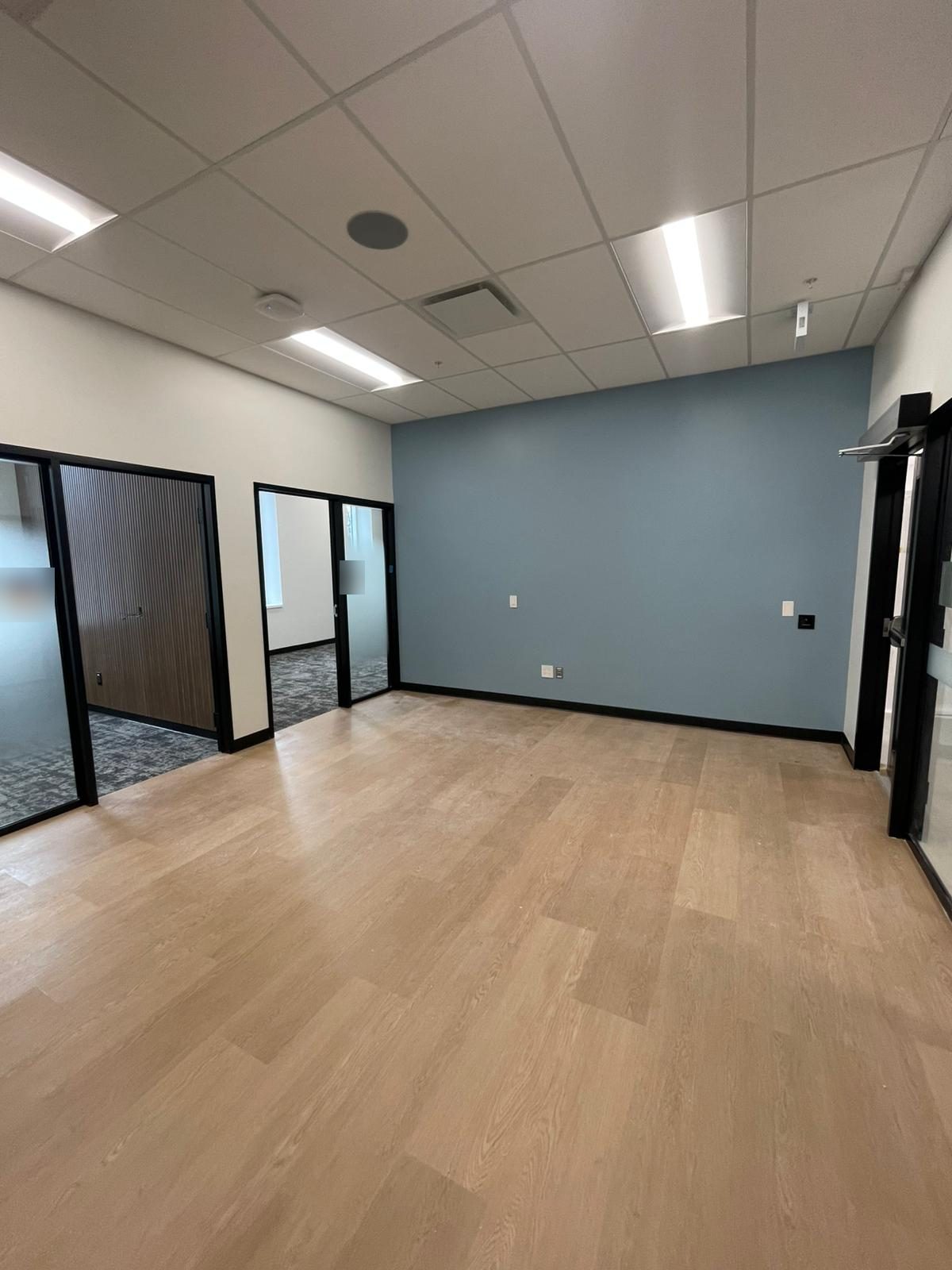 Soft blue painted accent wall in a renovated office area with glass-front rooms in Building B at Georgian College in Barrie