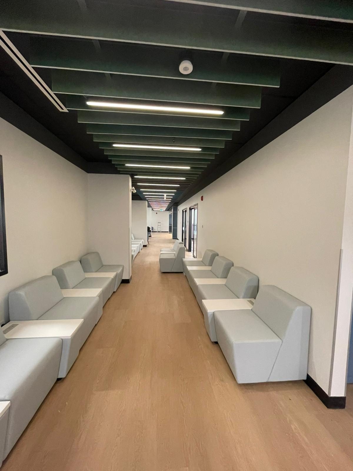 Lounge corridor with crisp white painted walls, slatted acoustic ceiling and modular seating in Building B at Georgian College in Barrie