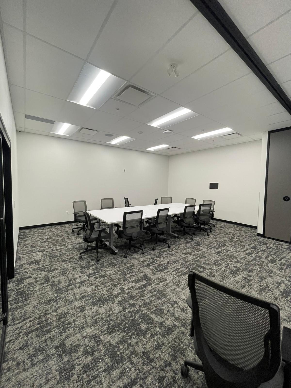 Renovated meeting room with clean white painted walls and a long conference table in Building B at Georgian College in Barrie
