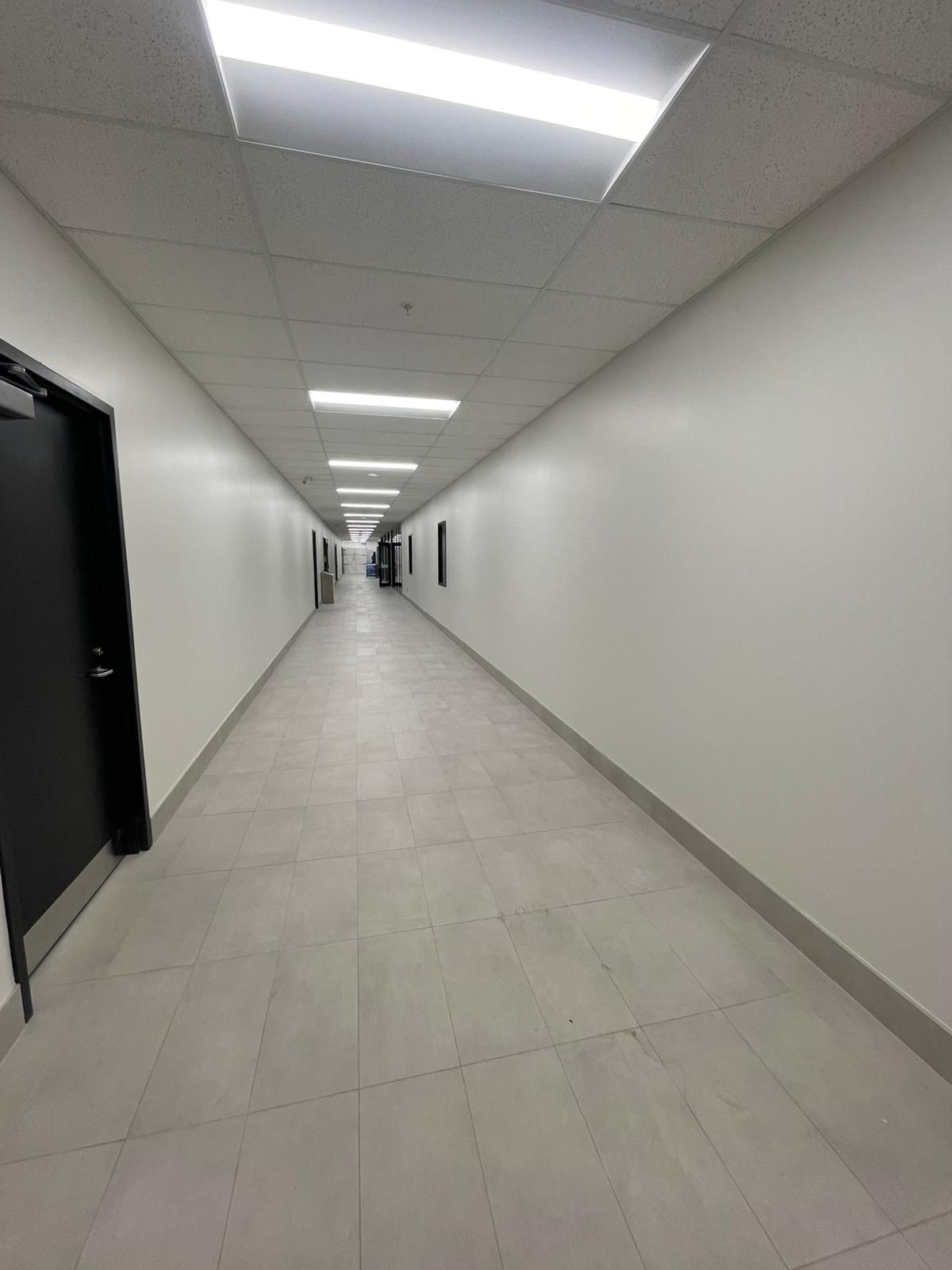 Long tiled service corridor with clean painted walls and dark doors in Building B at Georgian College in Barrie
