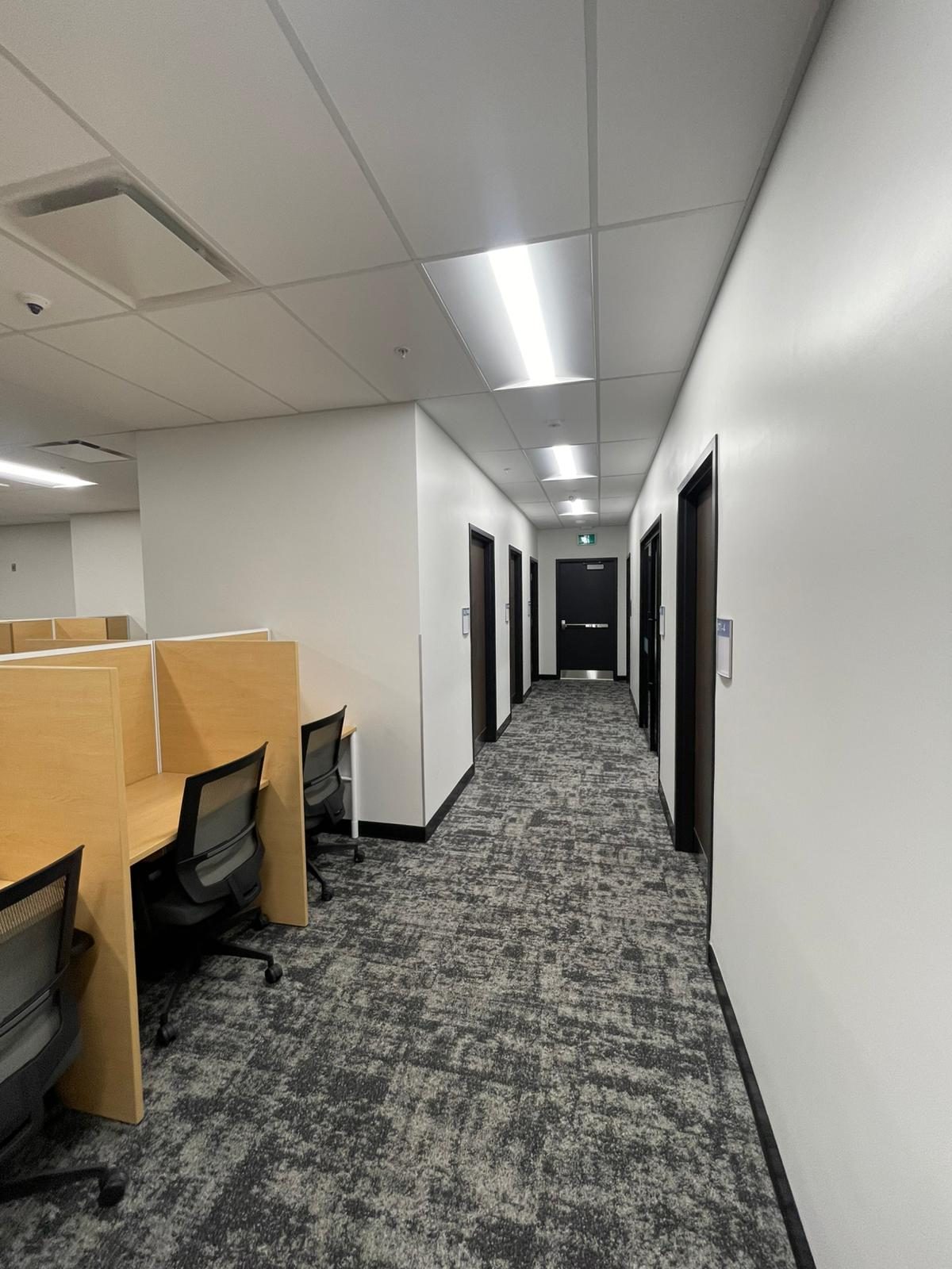 Hallway beside study carrels with smooth white painted walls and black door frames in Building B at Georgian College in Barrie