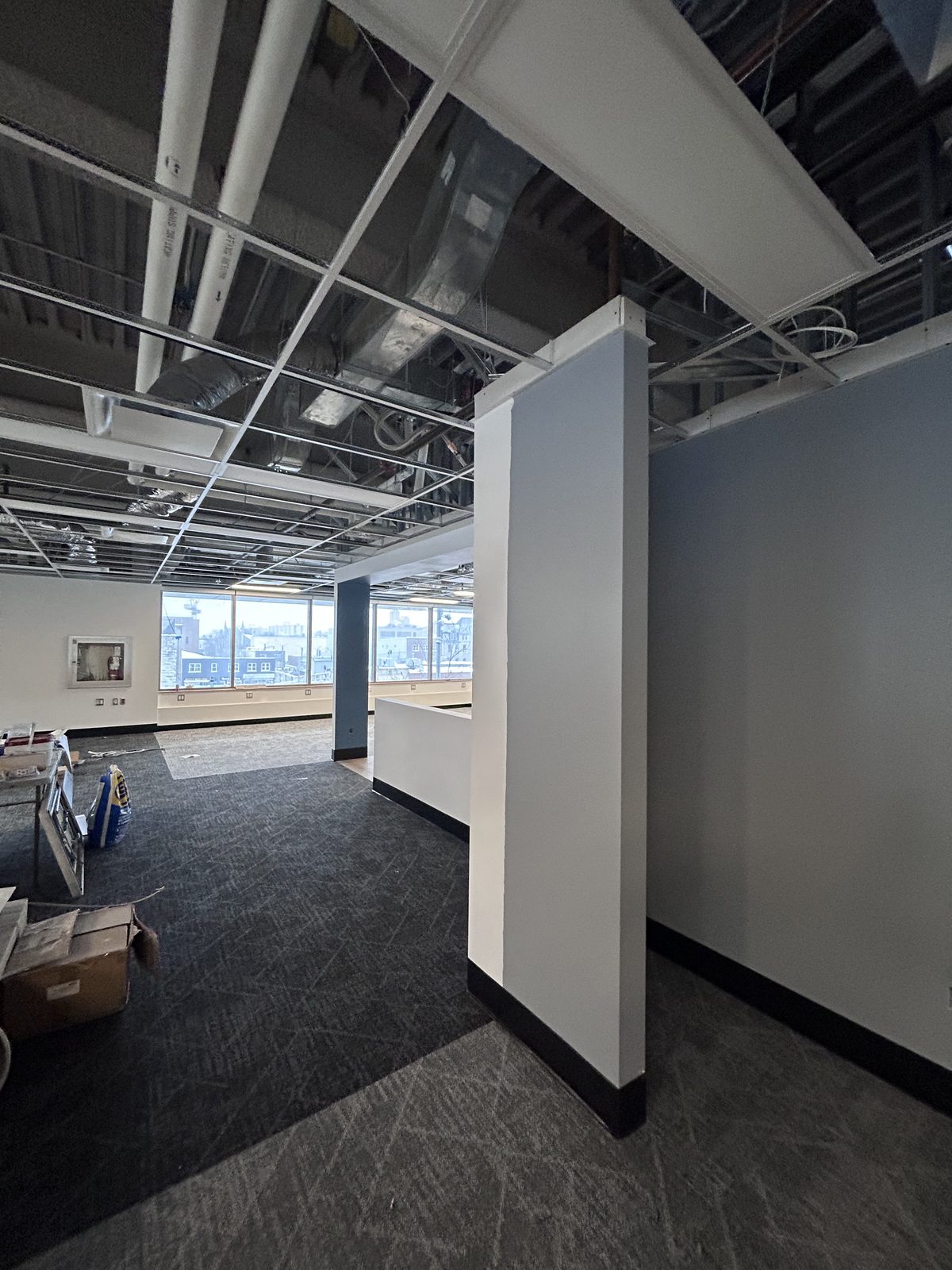 Blue and white painted column and low partition wall with black base, open ceiling grid and a window wall