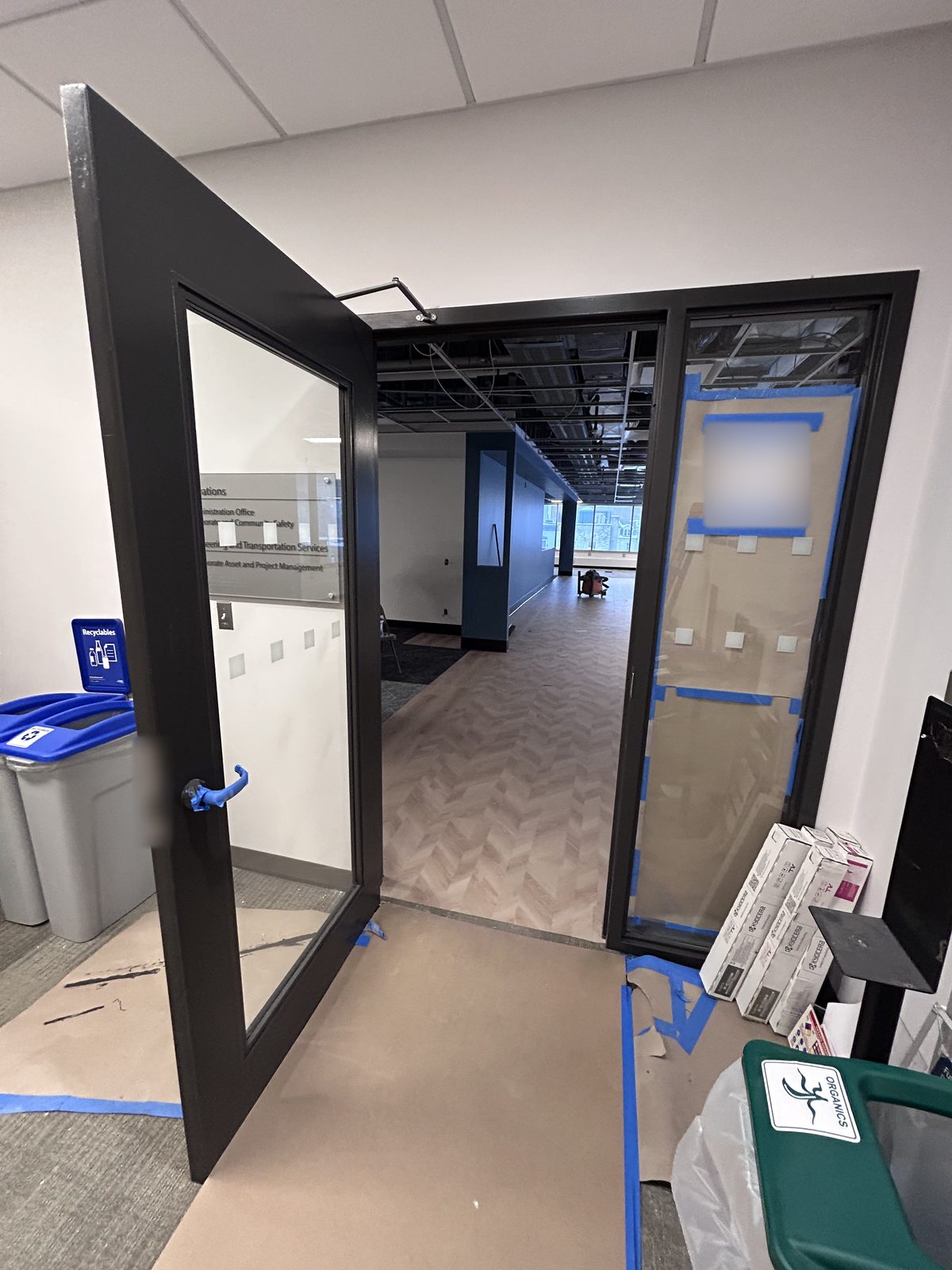 Open dark grey painted door and frame leading into a renovated area with floor protection