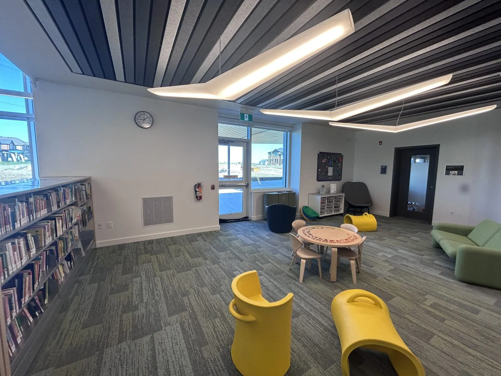 Children's area with small yellow seats, a low table, a green sofa and painted walls