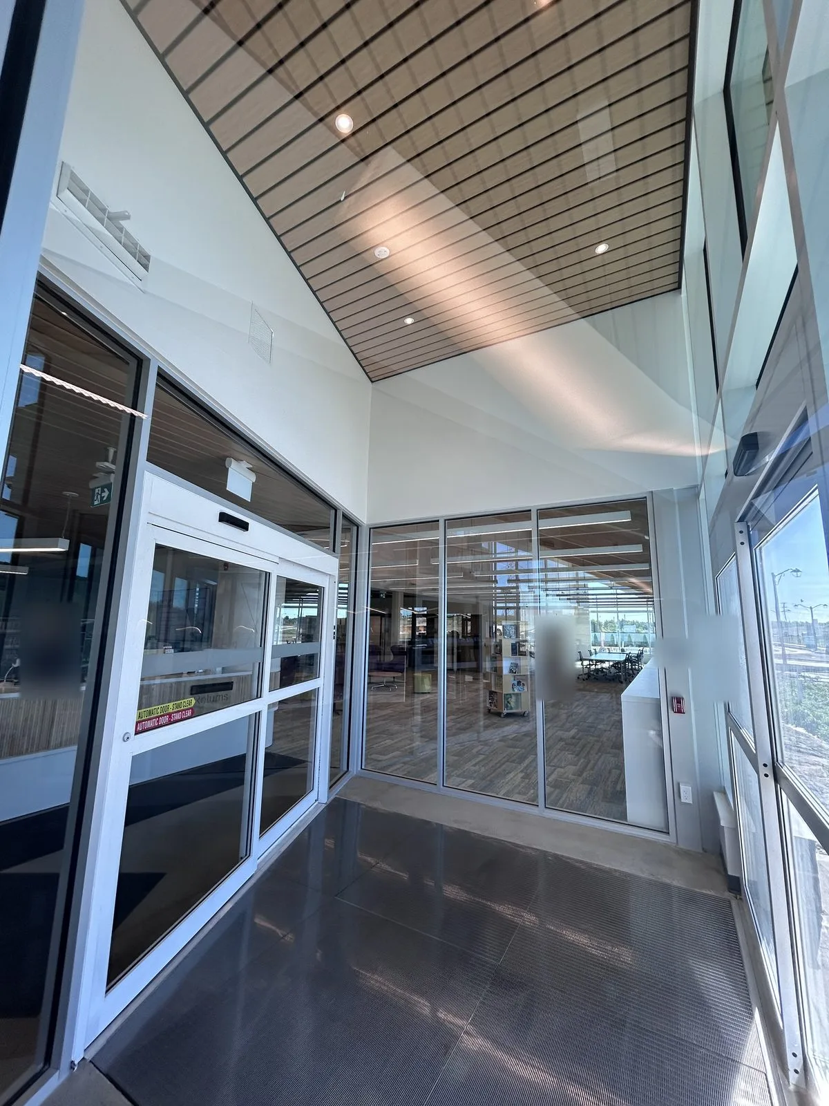 Entrance vestibule with glass doors, a wood slat ceiling and white walls