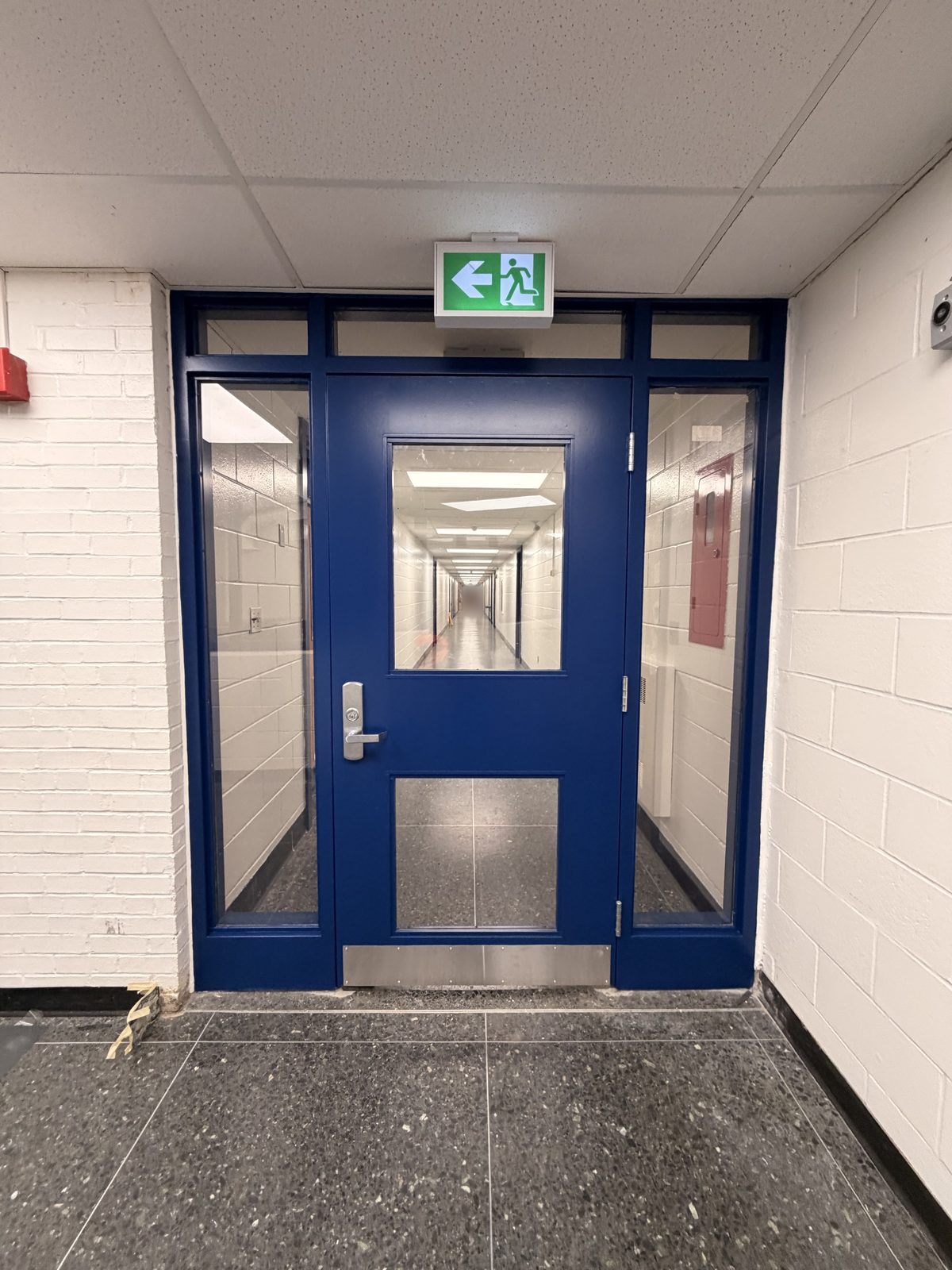 Dark blue painted door with matching sidelights and frame between white painted block walls at Roseneath Centennial School in Roseneath