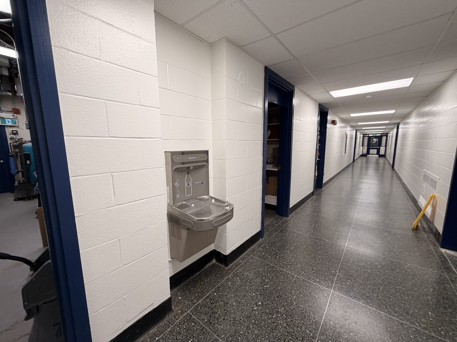 Corridor with white painted block walls, a bottle filling station and dark blue painted door frames at Roseneath Centennial School in Roseneath