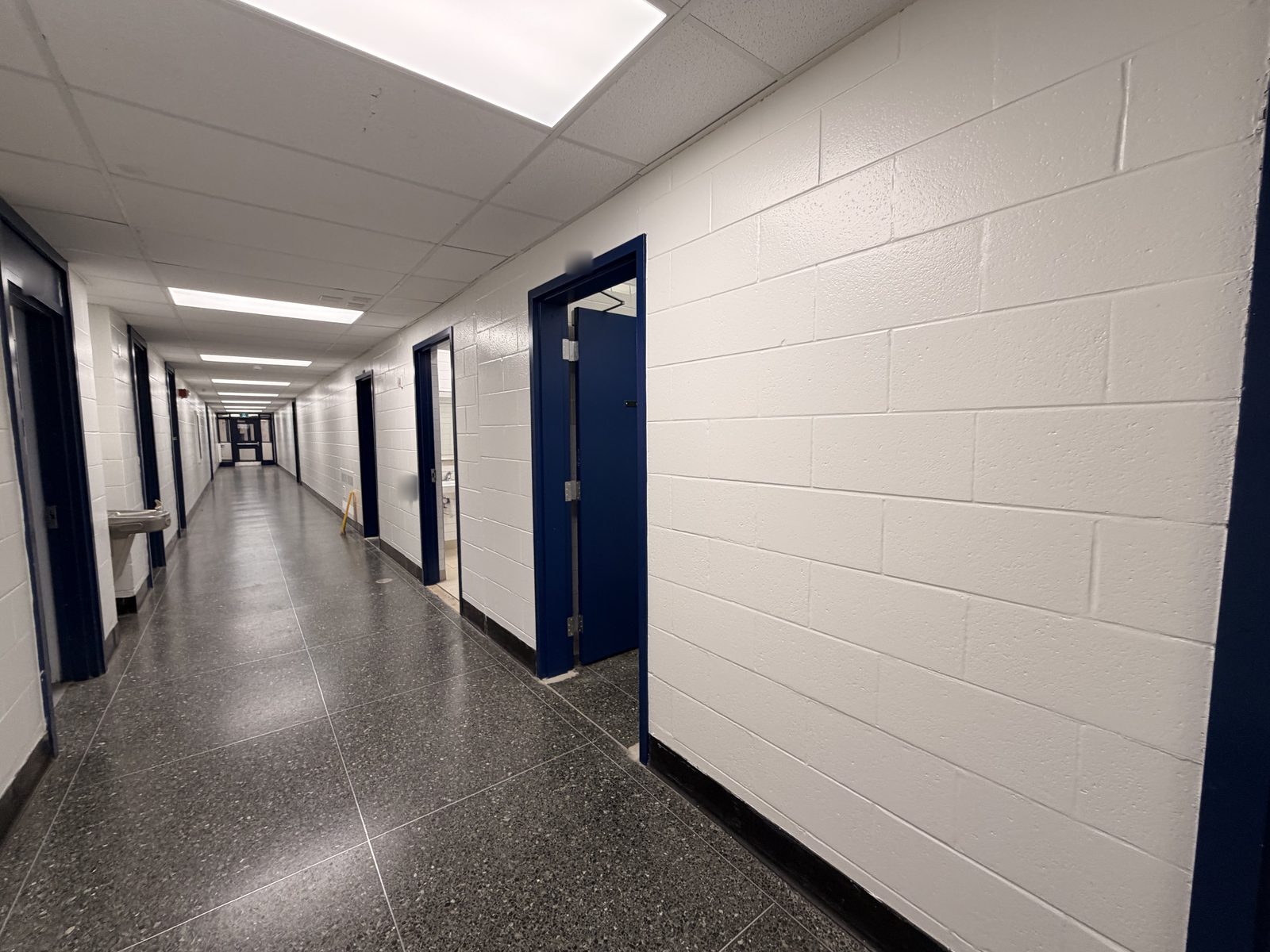 Long corridor with white painted block walls and dark blue painted door frames at Roseneath Centennial School in Roseneath