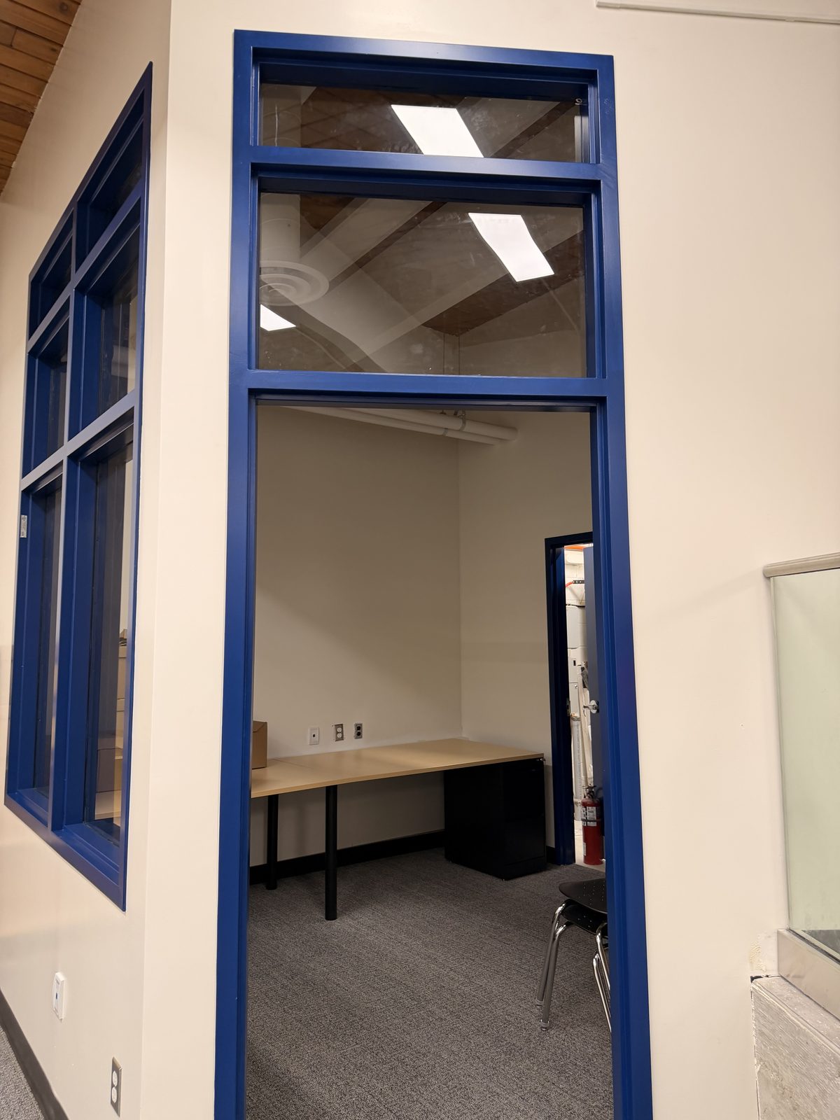 Office doorway with a blue painted frame and transom window in a cream painted wall at Roseneath Centennial School in Roseneath
