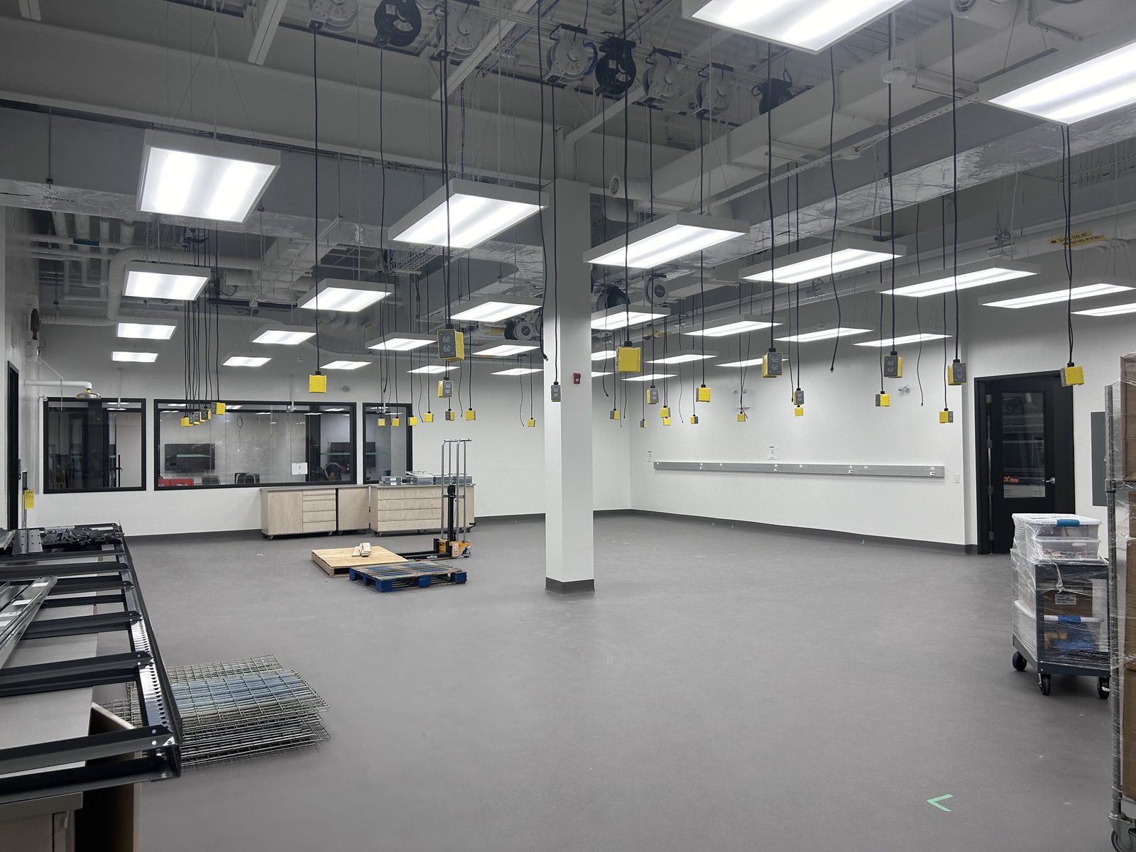 University of Waterloo โ Innovation Arena: open laboratory fit-out with suspended ceiling light panels, hanging power drops and clean painted floors